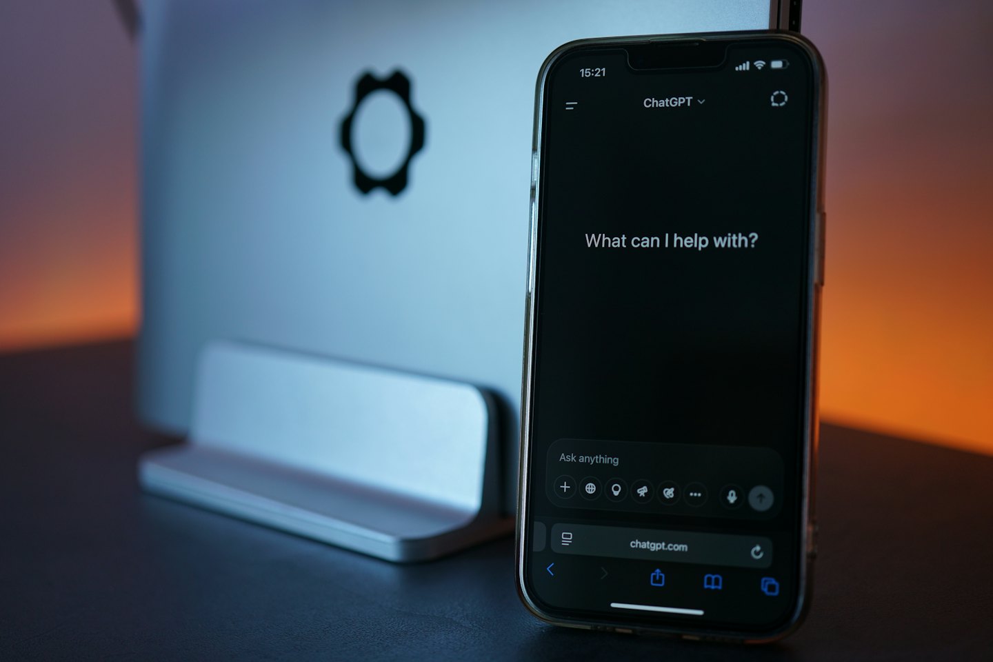 Smartphone displaying a chatbot interface sits before a laptop.