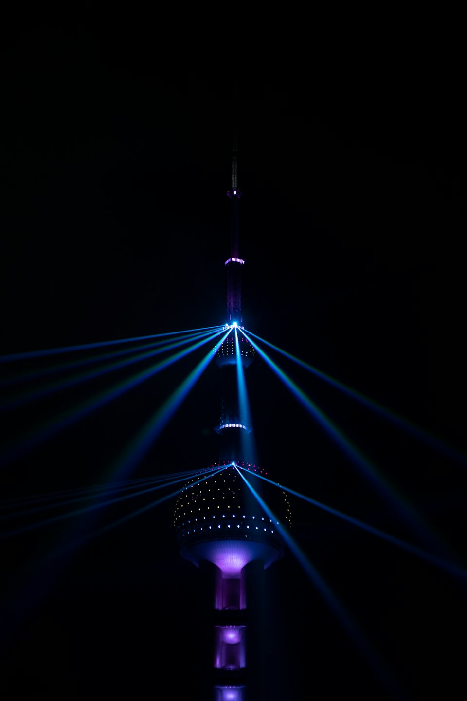 Modern communications tower glows with blue light at night.