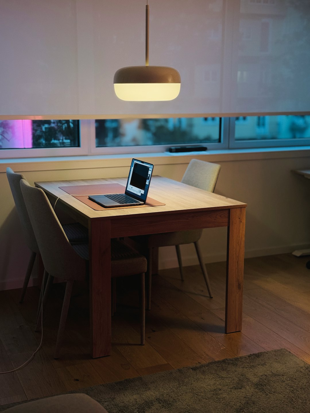 Open laptop sits on a wooden table in a home office.